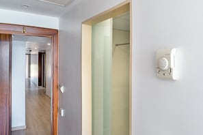 A hotel room with a wooden door, a glass shower enclosure, and a Honeywell thermostat on the wall. - Biniamar (Sant Llorenc des Cardassar)