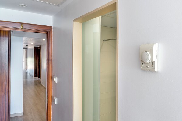 A hotel room with a wooden door, a glass shower enclosure, and a Honeywell thermostat on the wall. - Biniamar (Sant Llorenc des Cardassar)