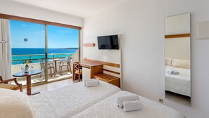 Ein Hotelzimmer mit Balkon, Schreibtisch, Bett und Fernseher.