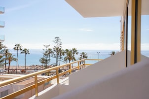 Un balcón con vista a la playa, palmeras y el océano.