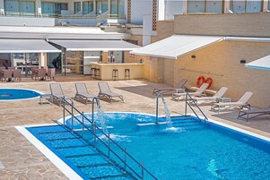 A swimming pool with multiple sun loungers and a bar area.
