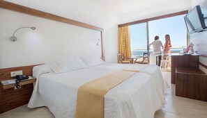 A hotel room with a bed, a desk, a chair, a TV, and a balcony with a view. - Biniamar (Sant Llorenc des Cardassar)