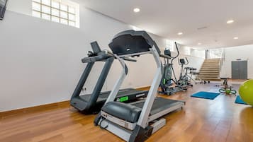 A gym with treadmills, elliptical machines, and a stairway.