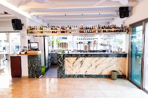 Un área de bar moderna con mostradores de mármol, una variedad de botellas de licor y una vitrina de vidrio.