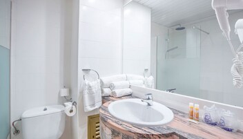 Un baño con inodoro, lavamanos y un espejo grande.