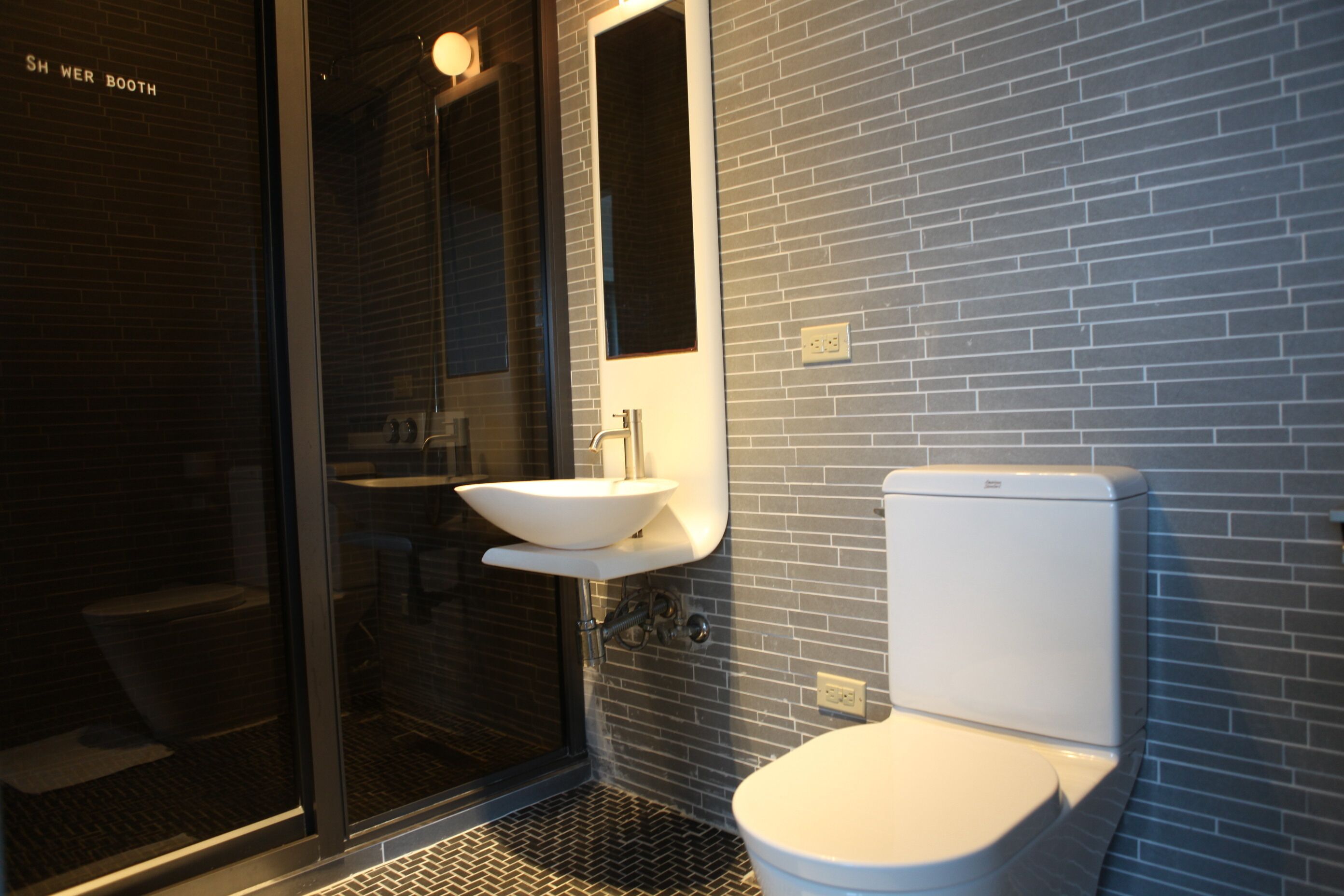 A modern bathroom with a glass shower enclosure, a white sink, and a toilet.