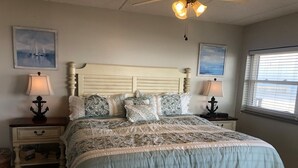 Ein Schlafzimmer mit einem großen Bett, zwei Nachttischen, einem Deckenventilator und zwei Wandleuchten.
