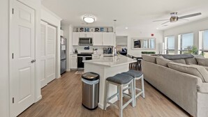 A modern kitchen with white cabinetry, a central island, and a ceiling fan. - The Ocean Bridge C34 - Beautiful Unit Across from Beach (Myrtle Beach)