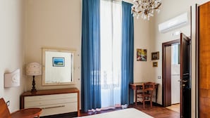 A bedroom with a bed, a desk, a chair, a dresser, a mirror, and a chandelier. - Grimaldi 8 Apartment by Wonderful Italy (Catania)