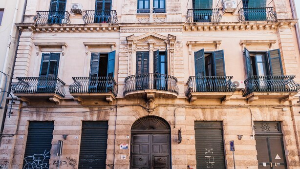 A multi-story building with balconies, a central entrance, and closed shutters. - Grimaldi 8 Apartment by Wonderful Italy (Catania)