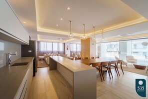 Relax in a spacious room with a central island workspace, comfortable seating area, and large windows.