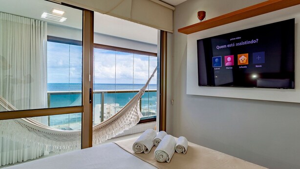 Habitación de hotel con un ventanal grande, una hamaca y un televisor mostrando un canal infantil.