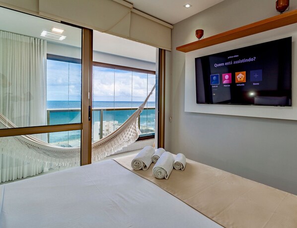 Relax in a spacious room with a large bed, flat-screen TV, and a hammock visible through the window.