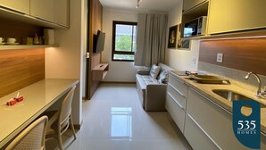 Una cocina moderna con zona de comedor, televisor integrado y una ventana con cortinas.