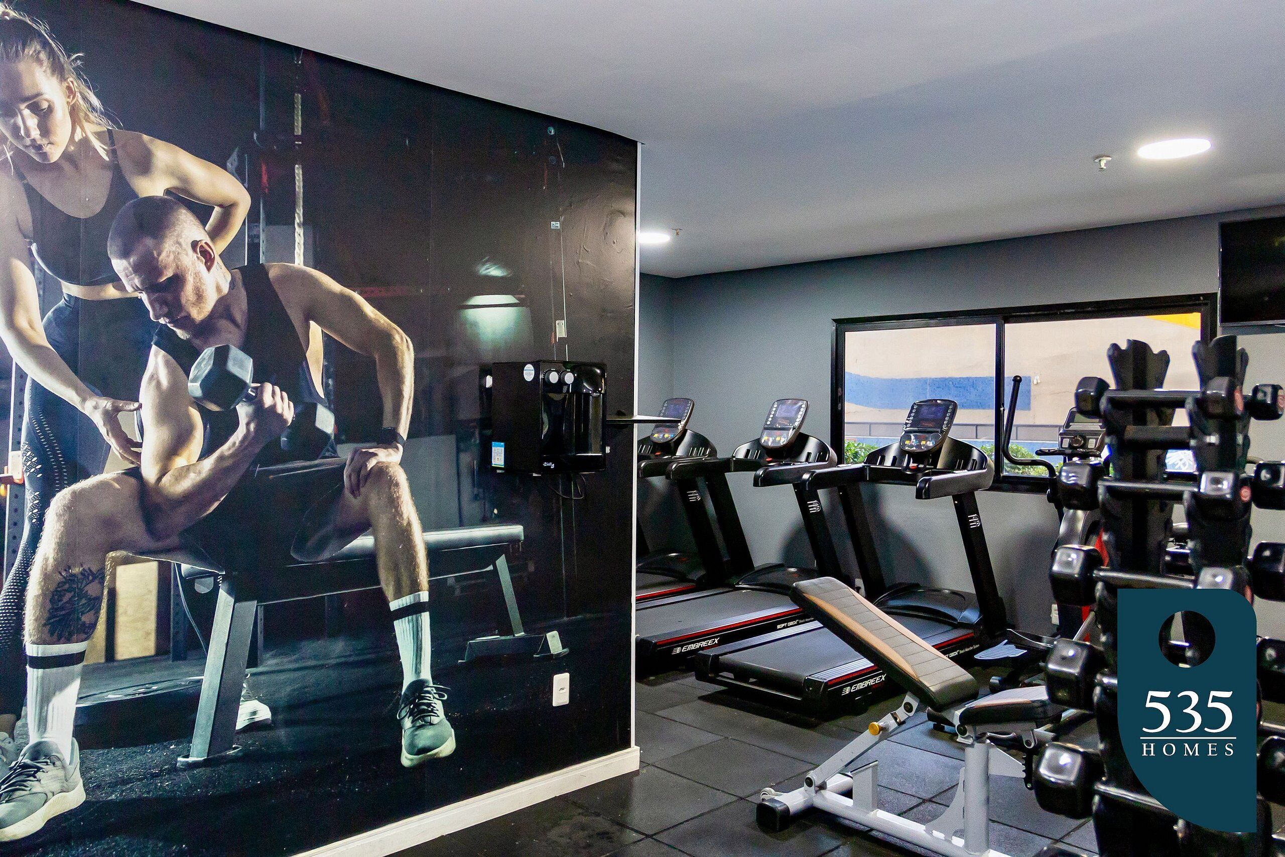 A gym with treadmills, weight machines, and a large mirror.