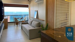 Un salon moderne avec un canapé, des fauteuils, une table à manger et une vue sur la mer.