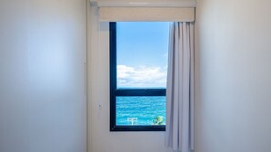 Una habitación con ventana que da a un cuerpo de agua, vista al mar y una cortina blanca.
