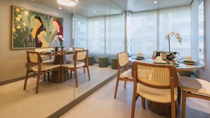 Un comedor moderno con un espejo grande, sillas de madera, una mesa redonda y un cuadro en la pared.