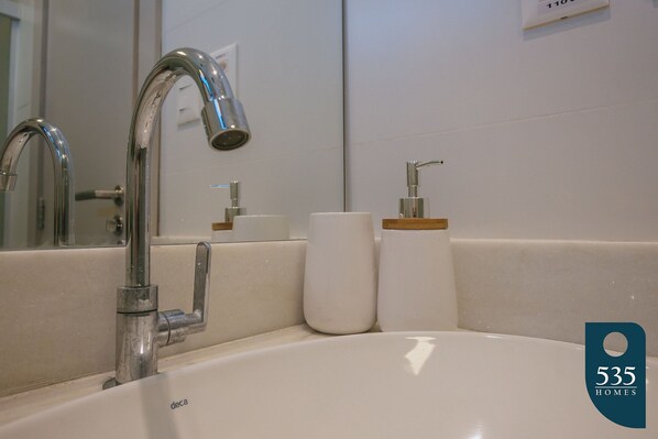 Un baño moderno con un lavamanos blanco, grifo cromado y un espejo.