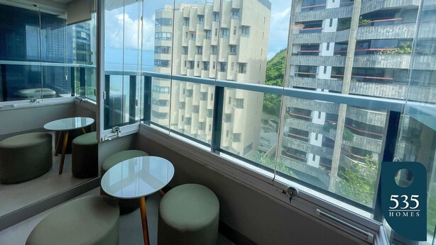 Habitación de hotel moderna con un ventanal grande, un balcón y vistas de edificios circundantes.