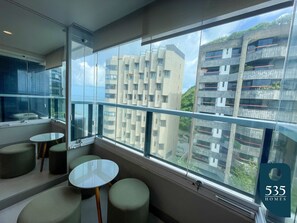 Habitación de hotel moderna con un ventanal grande, un balcón y vistas de edificios circundantes.