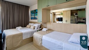 Une chambre d’hôtel avec deux lits, un grand miroir et vue sur la cuisine.