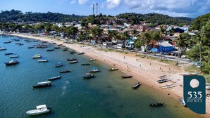 Une ville côtière où l’on peut voir de nombreux bateaux sur l’eau et une plage animée.