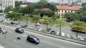 A city street with buildings, trees, and vehicles. - Red River Homestay (Hanoi)