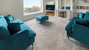 Ein Wohnzimmer mit Türkis-Sofas, einem Fernseher, einem Kamin und einem Bücherregal.