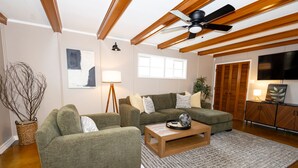 A living room with a sectional sofa, a coffee table, a floor lamp, and a ceiling fan. - New - Spacious 4B2B House in Tech Terrace (Lubbock)