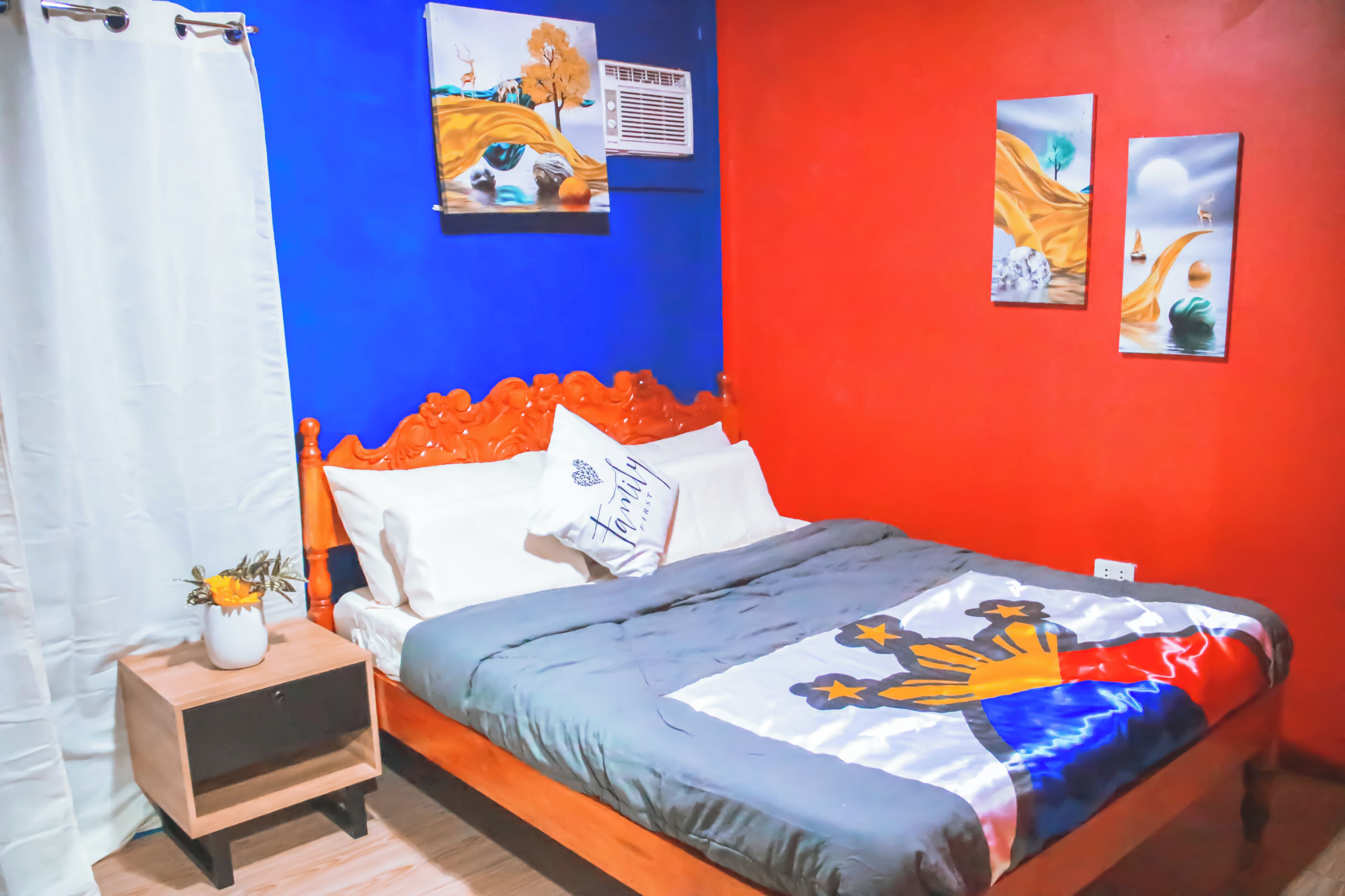Una camera da letto con un letto di legno, un comodino con un vaso e due opere d'arte appese alle pareti.