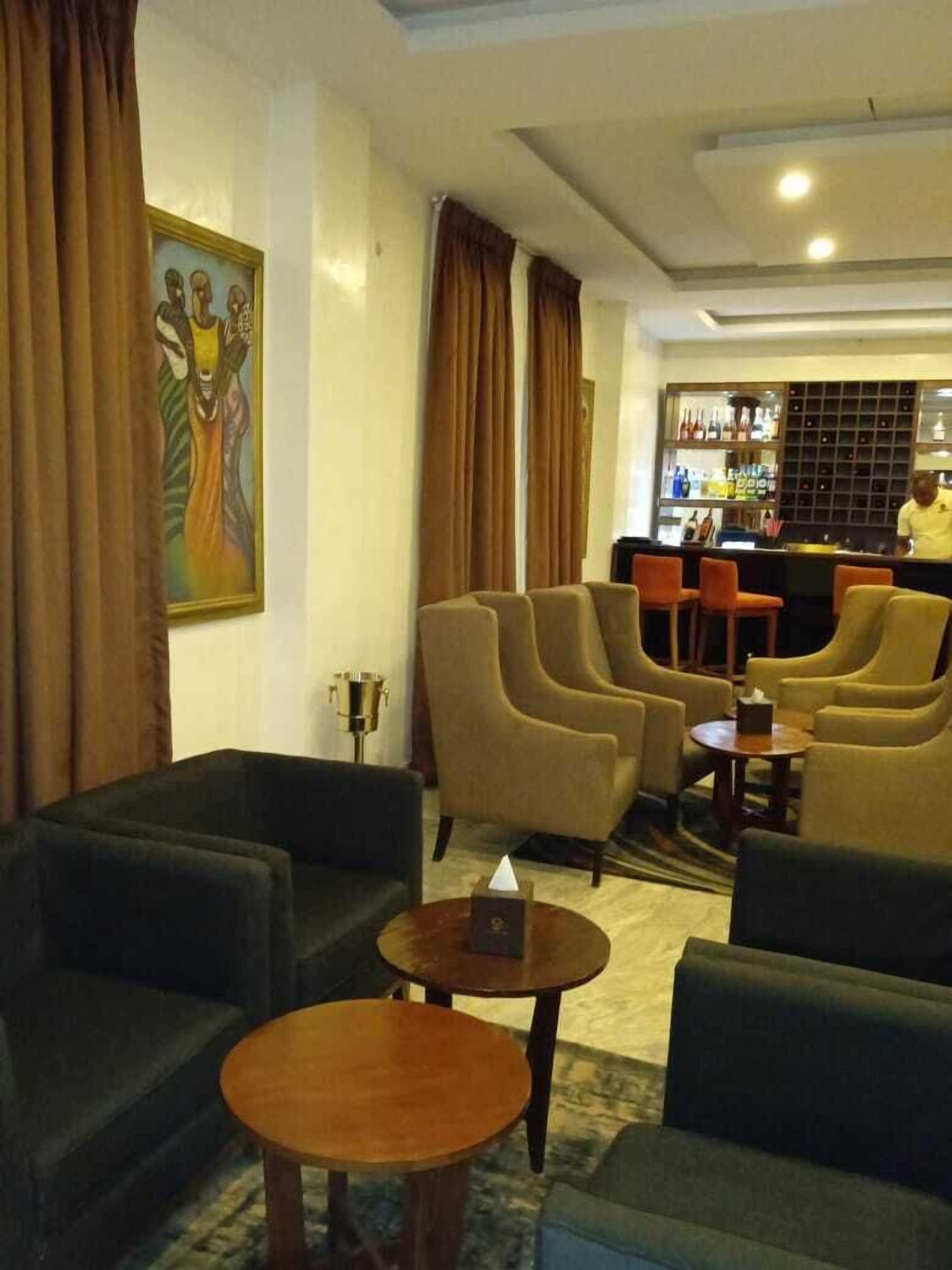 A lobby with sofas, a bar area, and a painting on the wall.