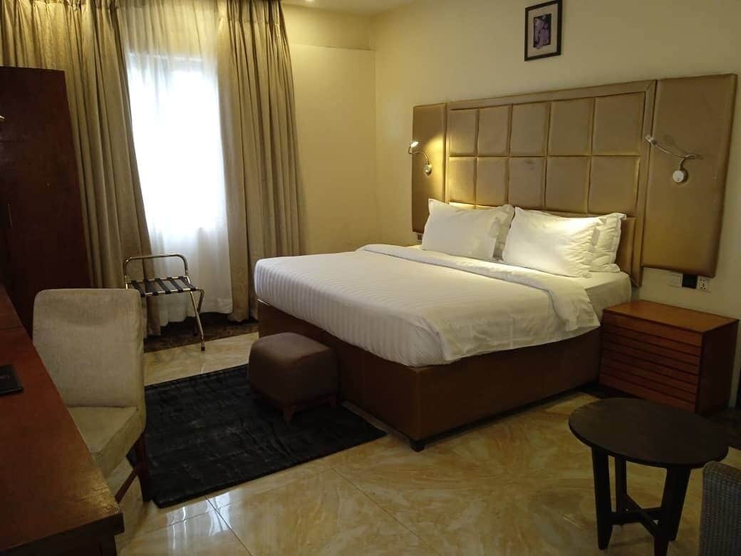Une chambre d’hôtel avec un grand lit, un bureau, une chaise et une petite table.