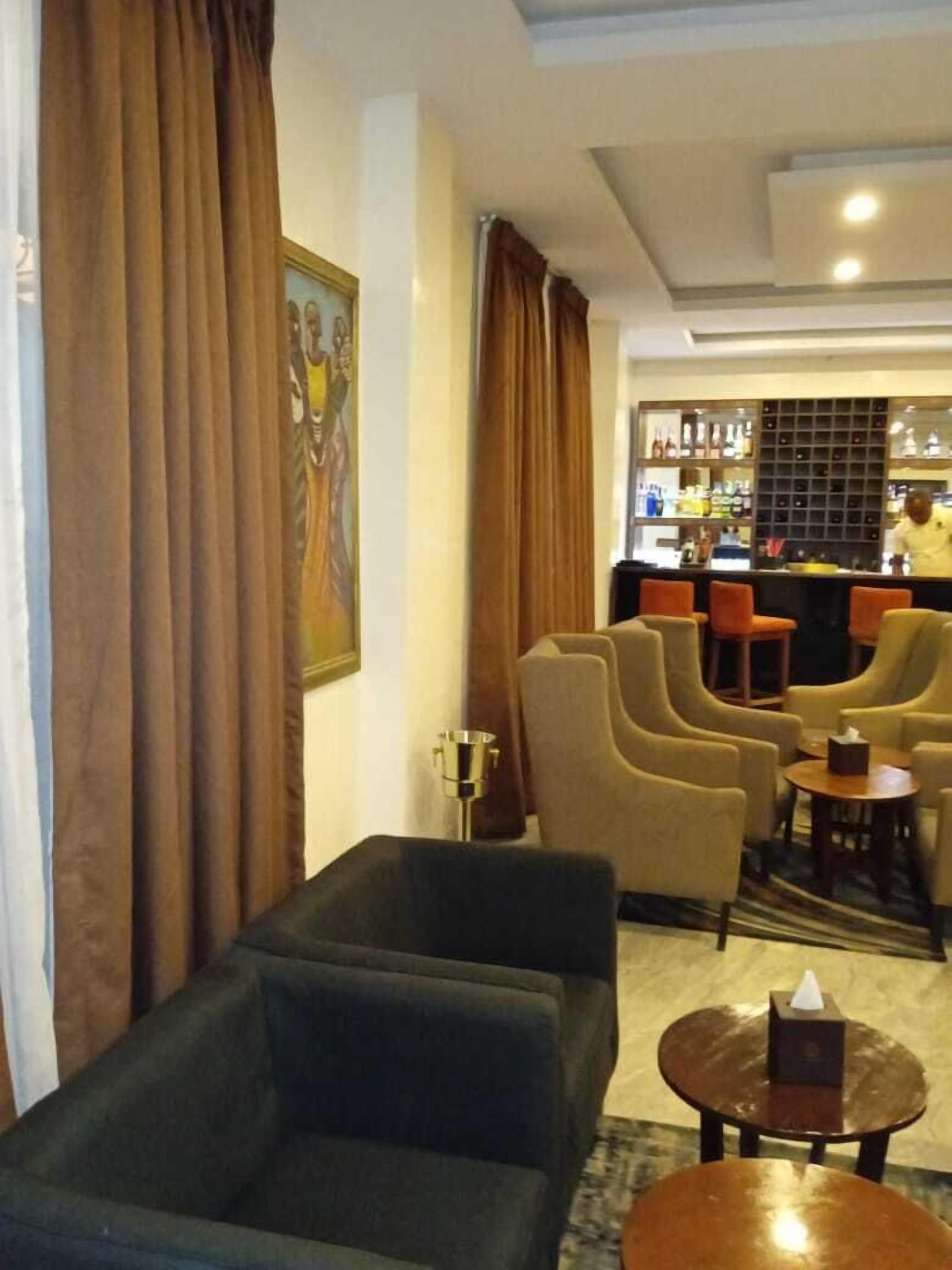 Un hall de hotel con zona de bar, asientos y un cuadro en la pared.