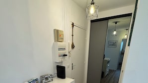 A modern, well-lit hallway with a white cabinet, a small heater, and a door leading to another room. - Large modern F3 - near port (Courseulles-sur-Mer)