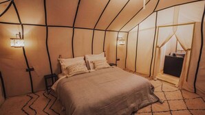 A cozy, tent-like bedroom with a bed, two bedside tables, and wall-mounted lamps.