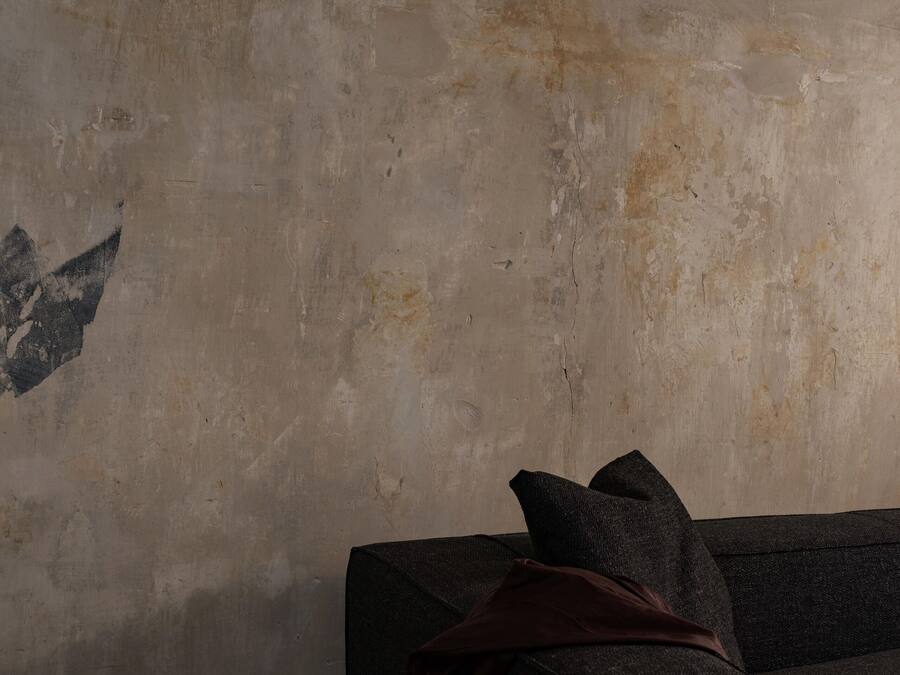 Ein Zimmer mit strukturierter Wand, einem dunklen Sofa und einer braunen Decke.