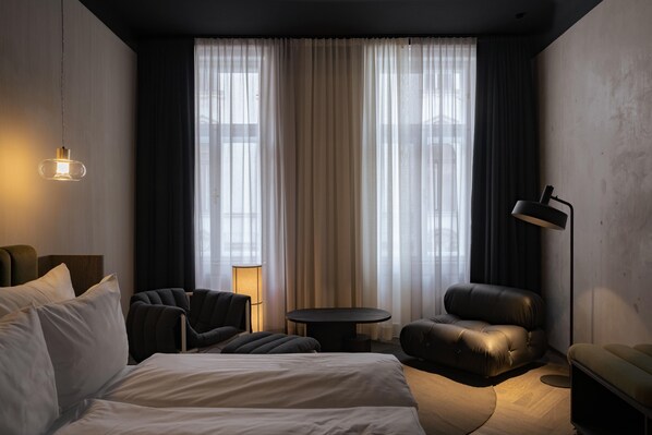 A modern hotel room with a large bed, two armchairs, a small round table, and a floor lamp. - rooms by wolfensson (Vienna)