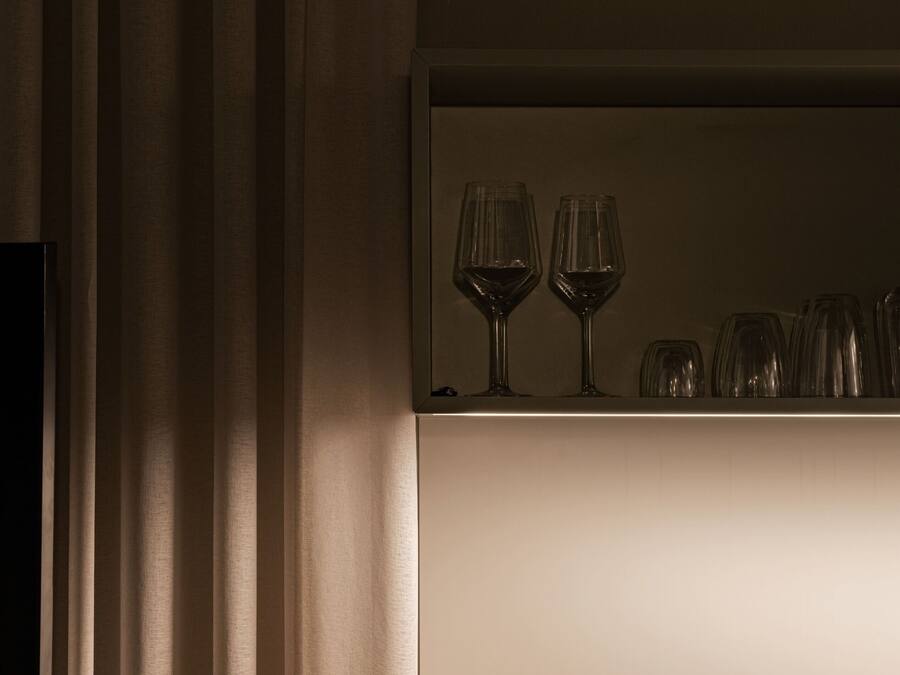 A kitchen area with a countertop holding wine glasses and a built-in stove.
