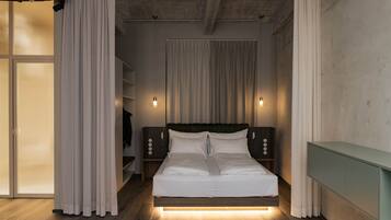 A modern bedroom with a bed, curtains, and ambient lighting.