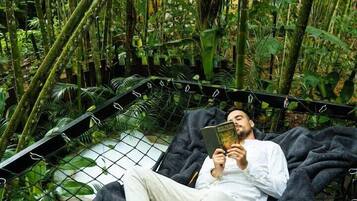 Una persona recostada en una hamaca en un exuberante bosque de bambú verde.