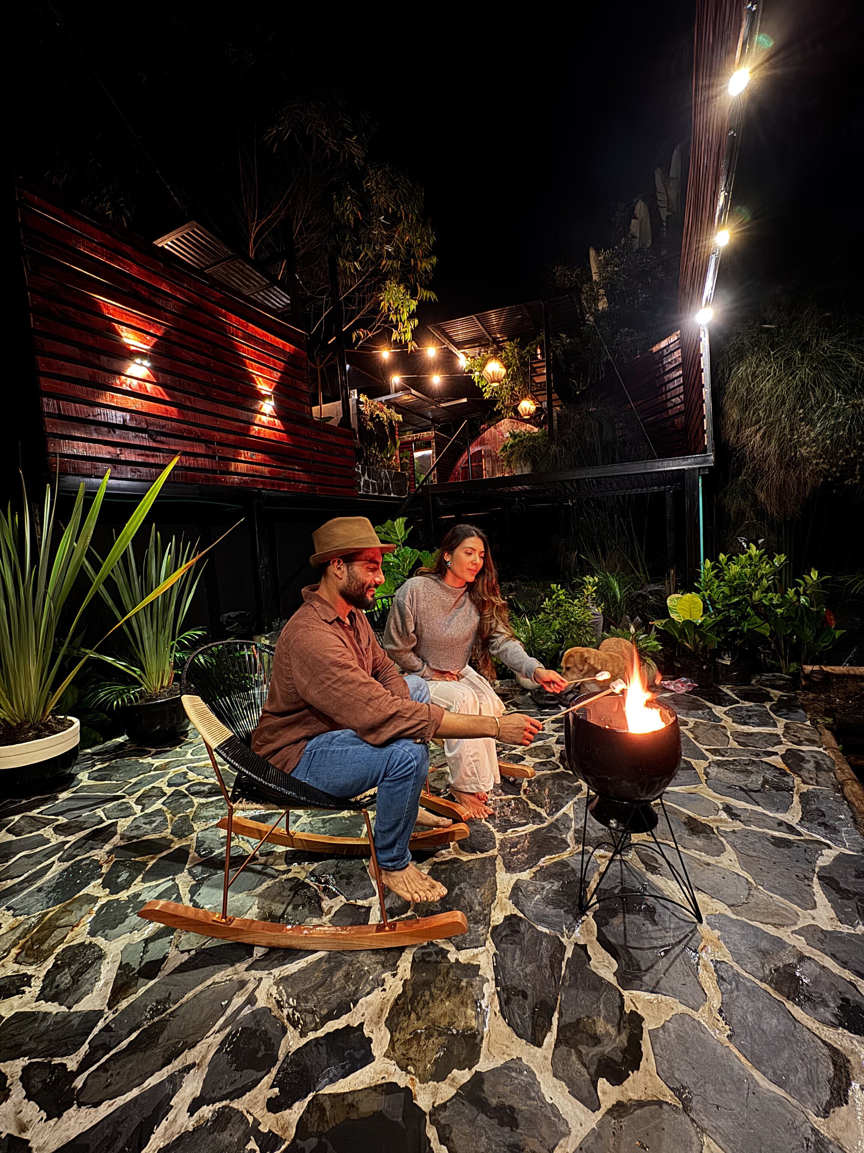 Una pareja sentada en mecedoras junto a un patio de piedra con una chimenea.