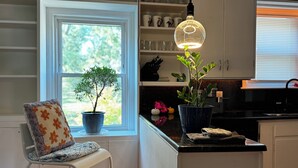Een keuken met een raam, een stoel, een potplant en een hanglamp.