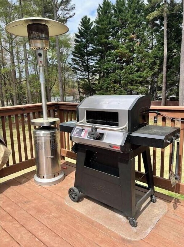 Een draagbare grill op een houten terras, met een metalen schoorsteen en een bedieningspaneel.