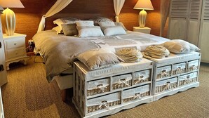 A bedroom with a canopy bed, two bedside lamps, a nightstand, and a chest of drawers with baskets. - Villa Campagne Chic (Meulers)