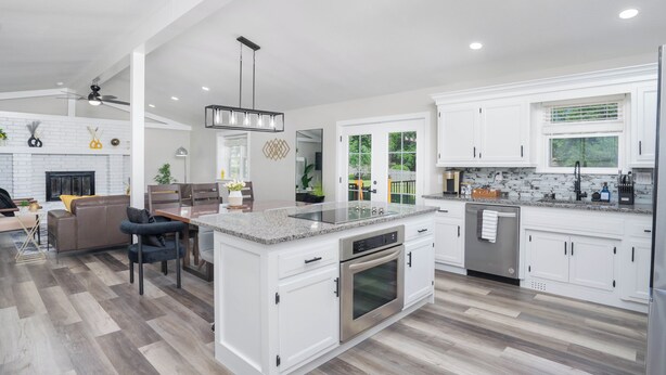 A spacious kitchen with white cabinetry, a central island, and a dining area with a sofa and chairs. - Modern House with King Suite! Relaxing Retreat!  (Springfield)