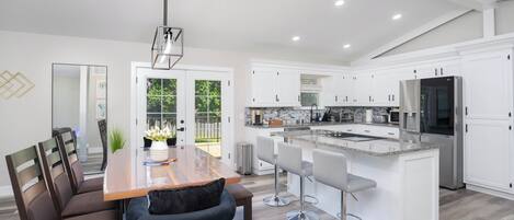 Una cocina moderna con armarios blancos, encimera de granito y electrodomésticos de acero inoxidable.