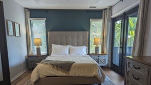 Een slaapkamer met een groot bed, twee nachtkastjes met lampen, een bankje en een dressoir.