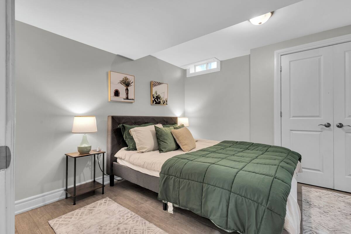A bedroom with a bed, bedside lamps, a nightstand, and artwork on the wall.