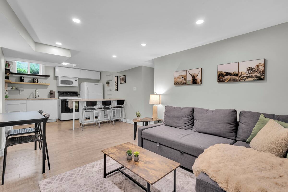 A modern living room with a grey sofa, a wooden coffee table, and a dining area with a table and chairs.